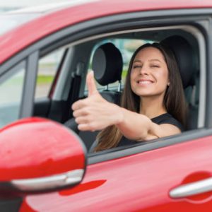 Car. Beautiful woman in the car shows thumbs up. Happy brunette in the car.